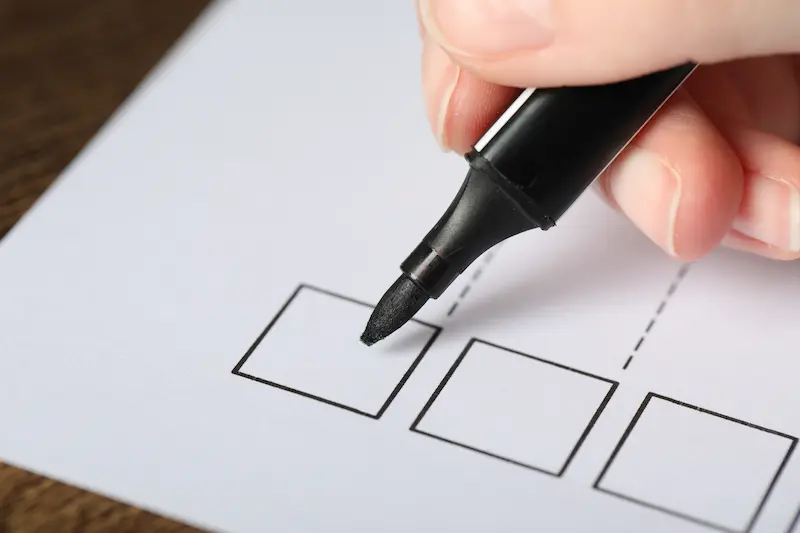 Paper with printed checkboxe, and woman's hand holding marker ready to write