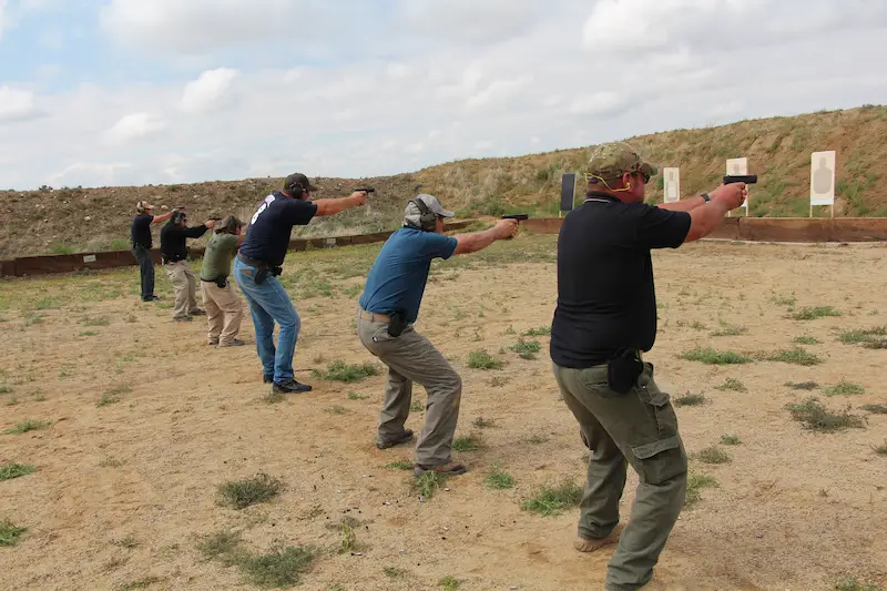 People standing in a line firing guns at targets