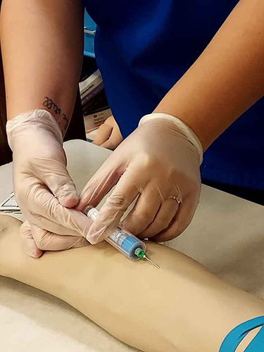 Nicci Sandoval is giving an intramuscular injection to the mannequin